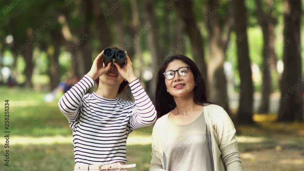 Teenage daughter and pretty mother sharing binocular in park Teenage daughter and pretty mother sharing binocular in park