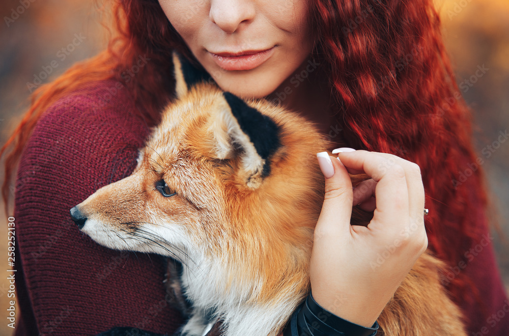 red-haired girl holding a fox in her hands