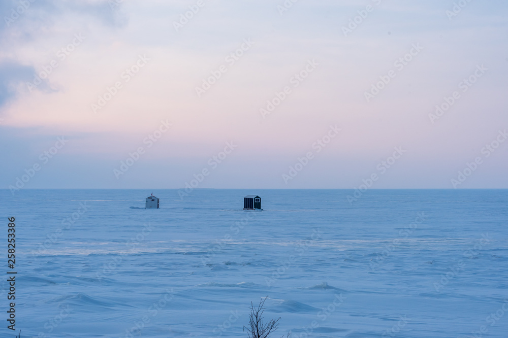 ice fishing shanty on lake at dusk