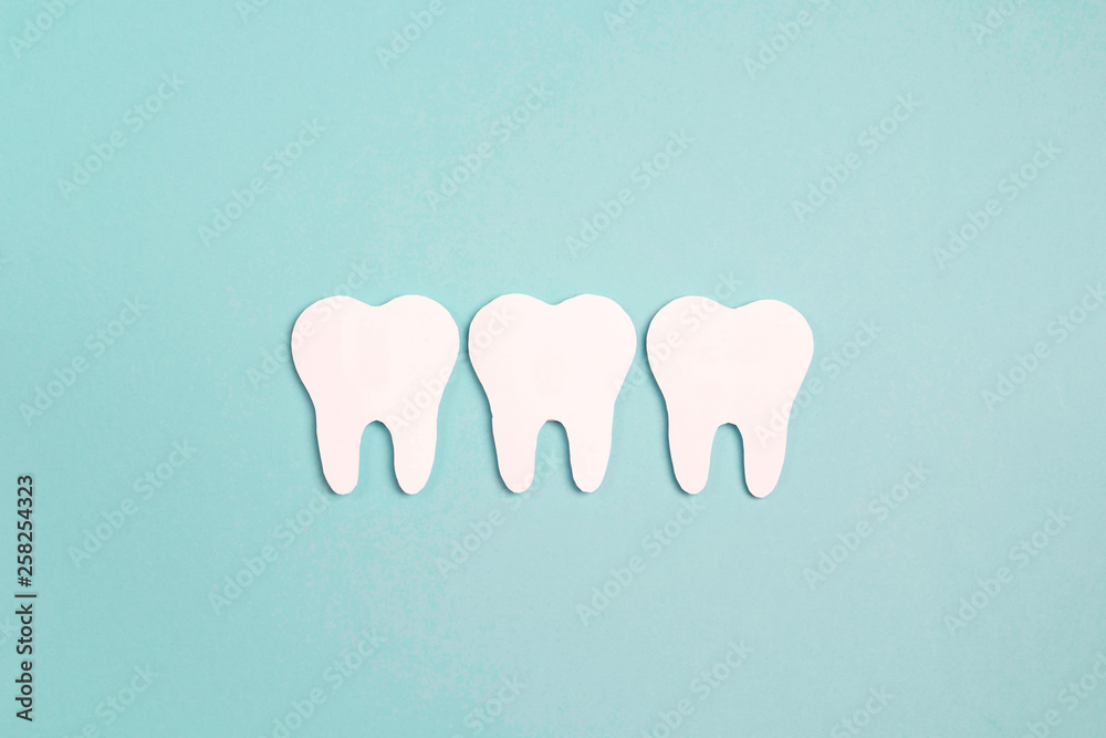 White paper teeth on blue background. Dental health concept. Flat lay, top view, copy space for text.