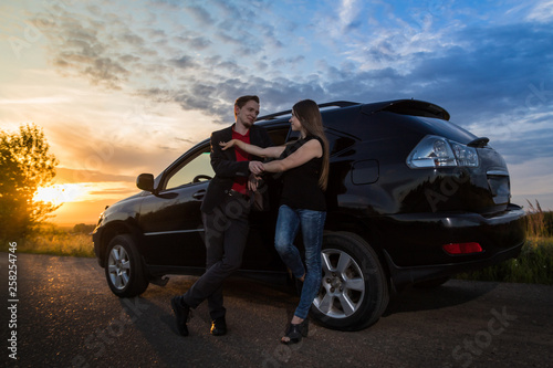 Couple standing near the car in a summer evening © keleny