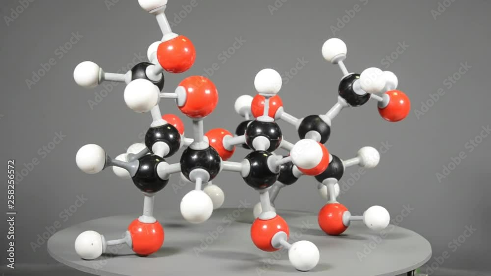 Molecule model of sugar (C12H22O11) visualizated by slow rotation. Red is oxygen, black is carbon, and white is hydrogen.