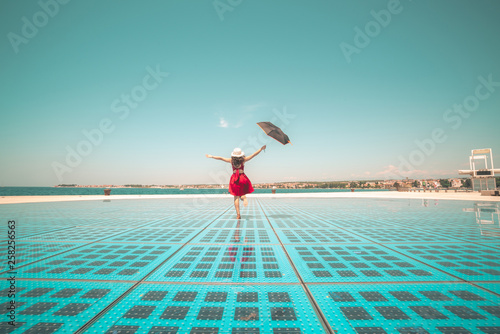 Happy woman traveler dances on outdoor disco floor in Zadar, Croatia.