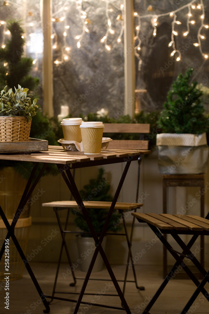 Winter. Street cafes. City, street, romantic date. Two cups of coffee, with a coffee. Coffee in a paper Cup. Wooden furniture in the cafe. Bench, vintage cafe.
