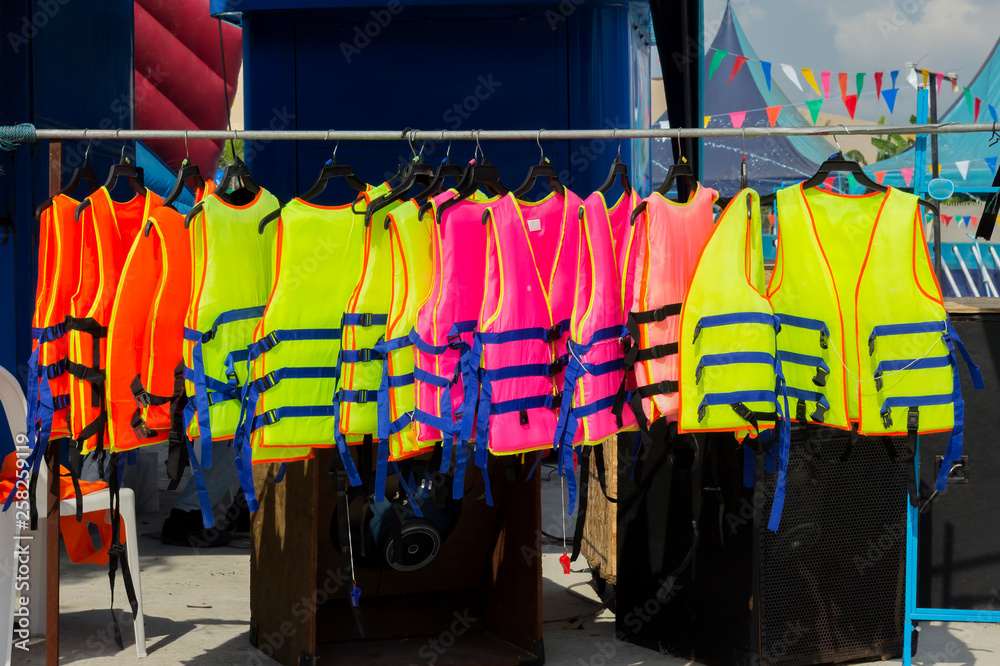 many colorful life jacket or life vest hanging on a clothesline