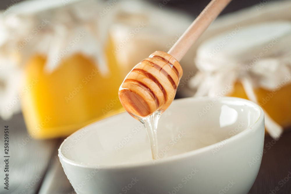 Honey background. Sweet honey in glass jar on wooden background. Honey background. Sweet honey in glass jar on wooden background.