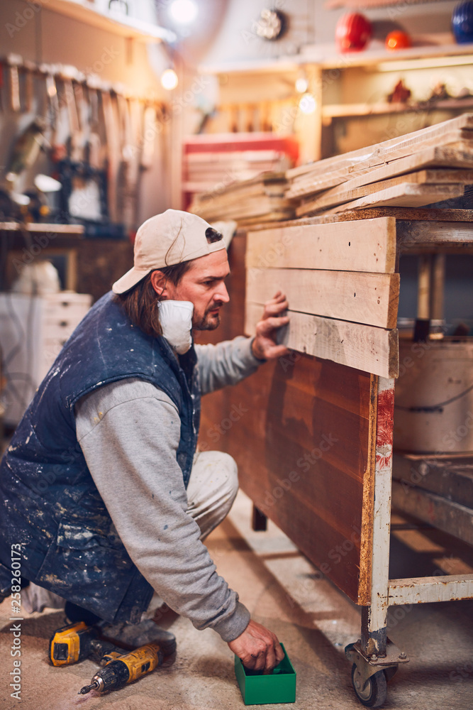 Male carpenter working on old wood in a retro vintage workshop. Male carpenter working on old wood in a retro vintage workshop.