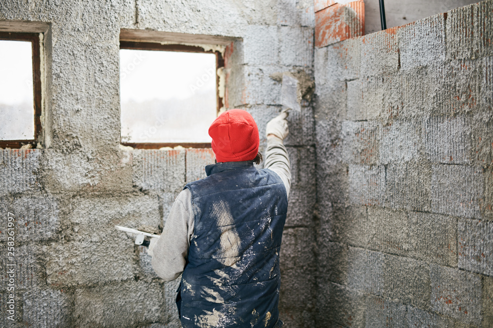 Real construction worker making a wall inside the new house. Real construction worker making a wall inside the new house.