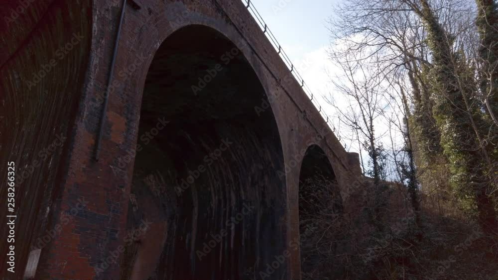 Tall arched brick railway bridge over a shallow stream in the countryside Tall arched brick railway bridge over a shallow stream in the countryside