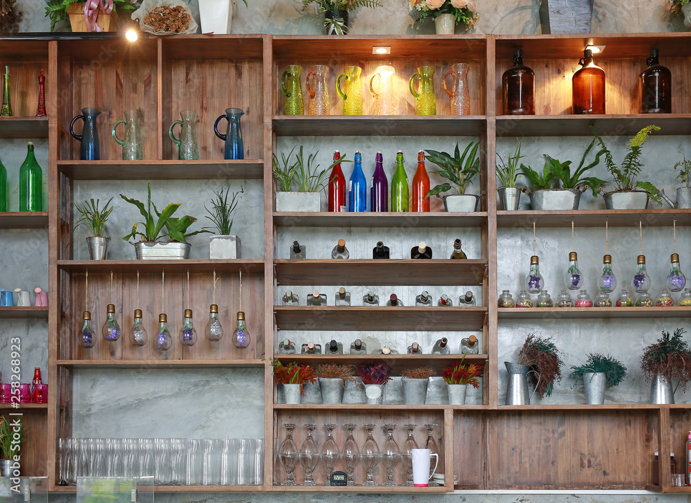 Utensils on shelves of cafe. bottles, flower, glass, jars and tree.
