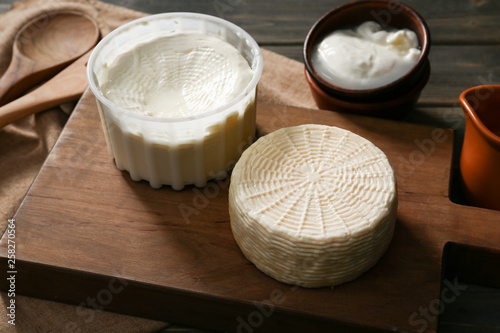 Wooden board with tasty cheese on table photo