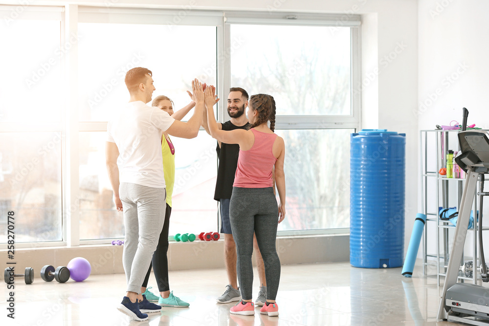 Sporty young people putting hands together in gym Sporty young people putting hands together in gym