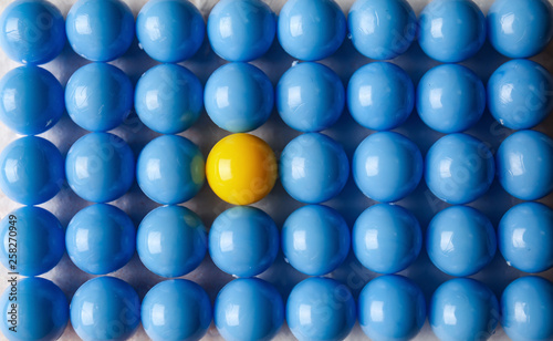 Yellow ball among blue ones, top view. Concept of uniqueness