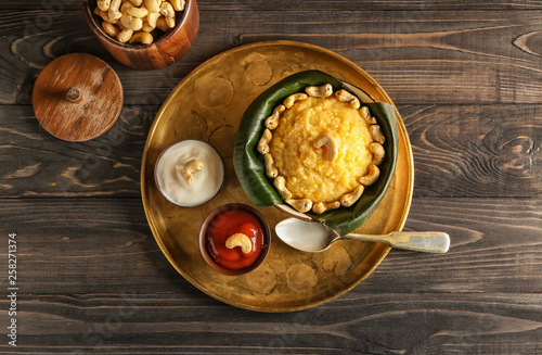 Bowl with traditional Indian food pongal on wooden table