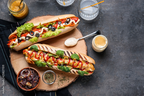 Canvas Print Tasty hot dogs with sauces on grey table