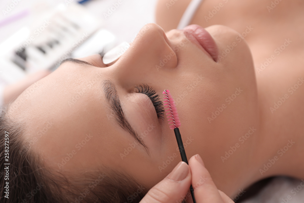 Young woman undergoing eyelash extension procedure in beauty salon