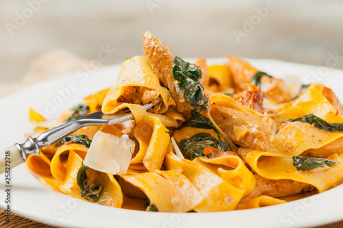 Italian salad, pappardelle pasta, with spinach, grilled chicken and dried tomatoes, sprinkled with flakes of cheese.