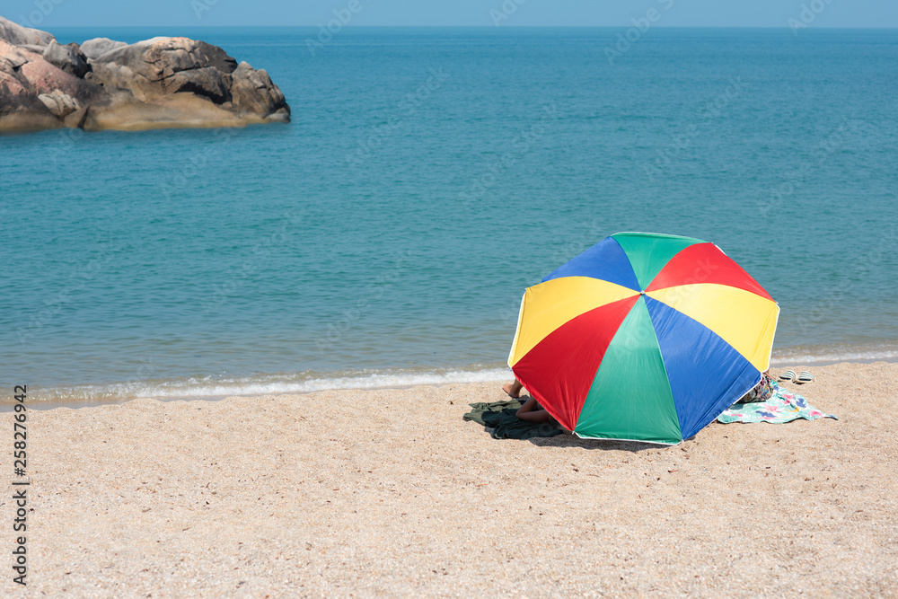 multicolor beach parasol gamp umbrella pin on the sea beach at sunlight of day time, protect sunshade for tourist in summertime, travel on the sea beach in vacation long weekend