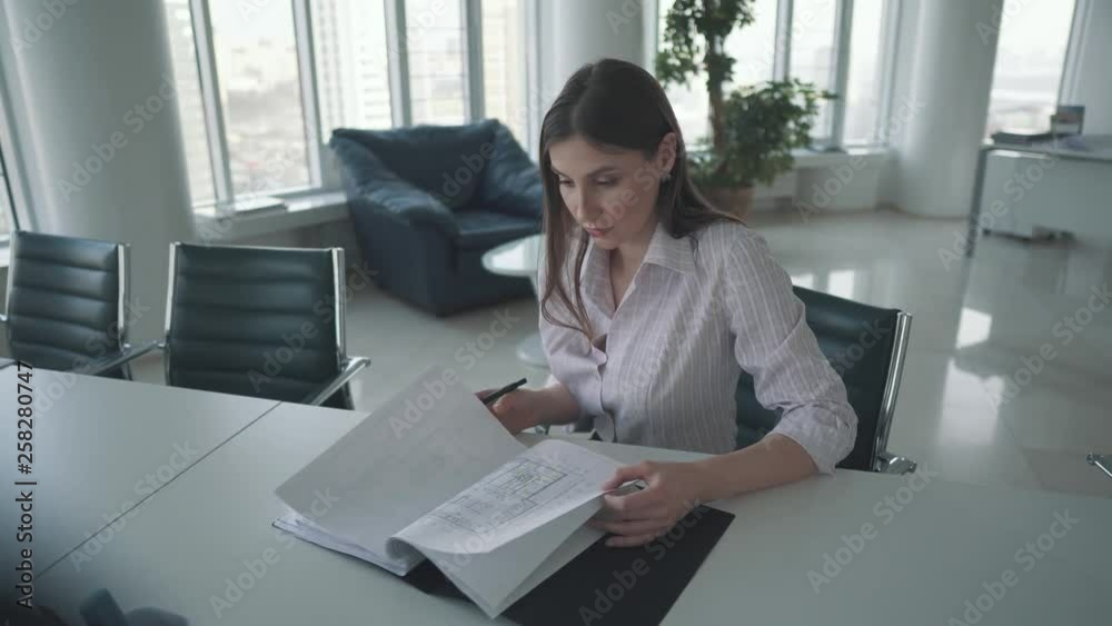 young employee working at the table in the office. attractive business woman looking through documents young employee working at the table in the office. attractive business woman looking through documents