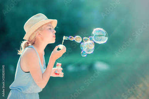 Teenage girl blowing soap bubbles outdoors