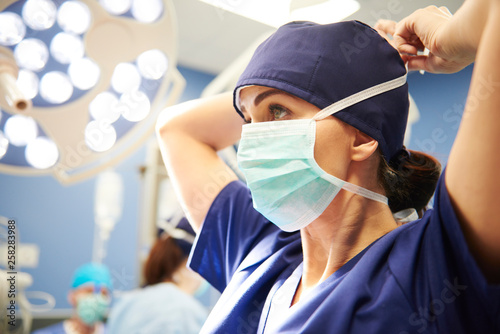 Side view of young female surgeon tying her surgical mask photo