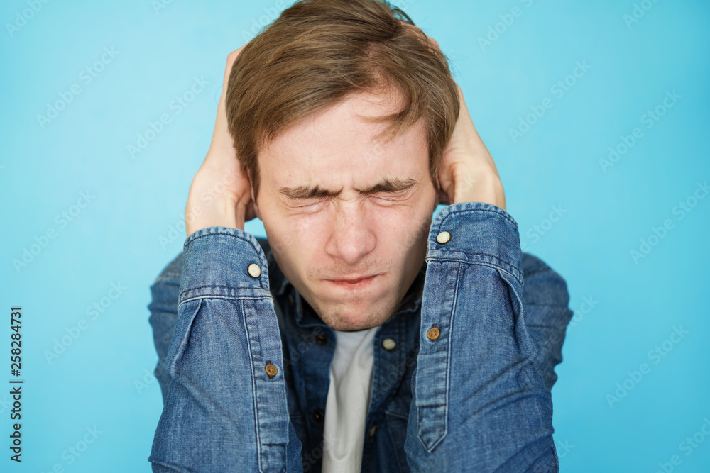 young aggressive male teenager in denim shirt on blue background young aggressive male teenager in denim shirt on blue background