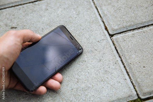 Foto Ma is holding broken smartphone lying on the road outdoors