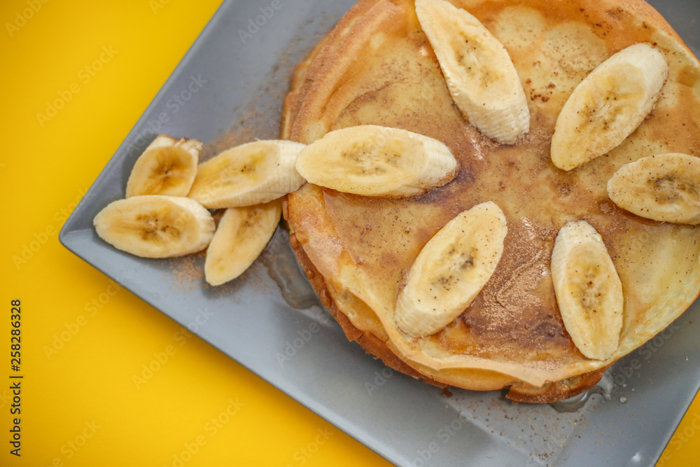 Stack of traditional russian pancakes blini with bananas and honey on yellow background. Homemade russian thin pancakes blini. Russian food, russian kitchen. Stack of traditional russian pancakes blini with bananas and honey on yellow background. Homemade russian thin pancakes blini. Russian food, russian kitchen.