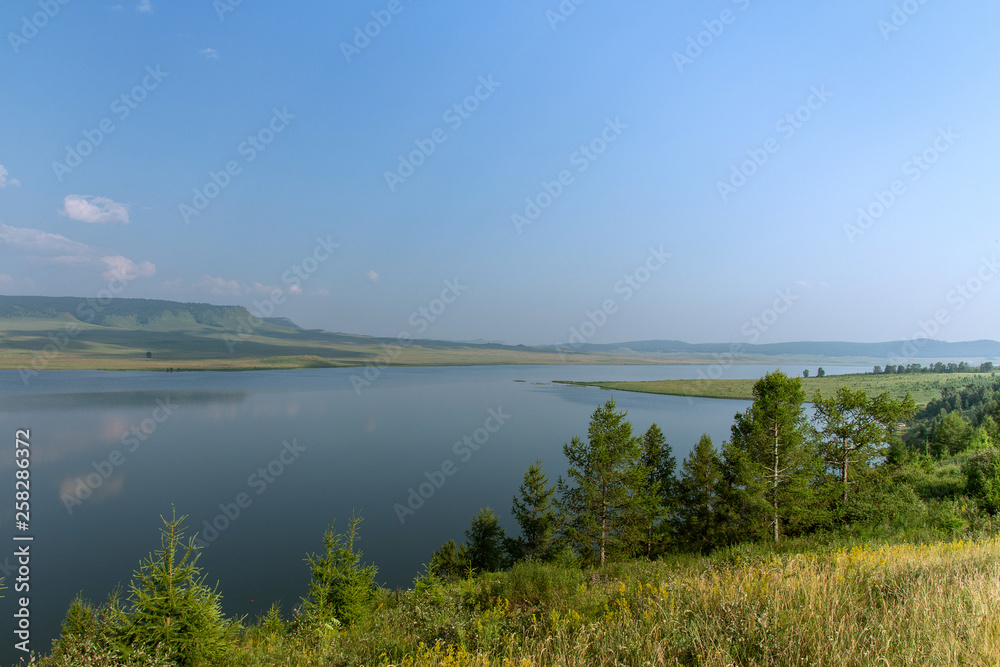 Beautiful view on lake and mountains on a sunny and bright day. Summer landscape, blue sky.