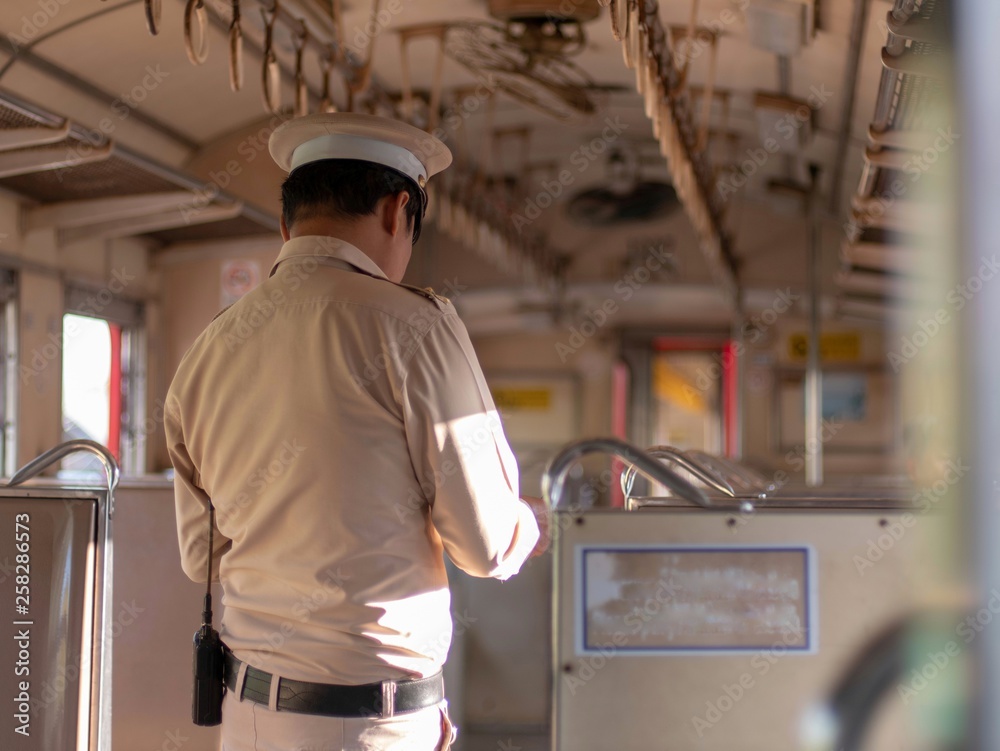 The train officers are checking passenger tickets on the train
