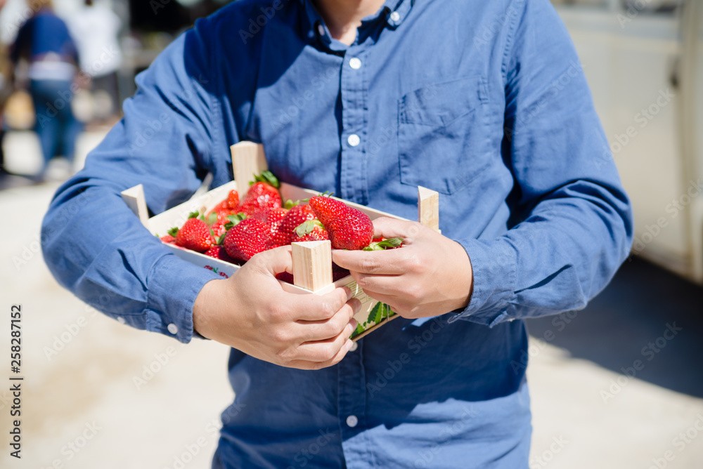 Person holding bag with healthy nutritious strawberries on groceries shopping market background, closeup top side view image Person holding bag with healthy nutritious strawberries on groceries shopping market background, closeup top side view image
