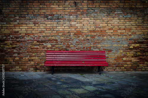 La solitudine di una panchina rossa e vuota photo