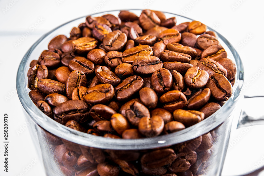 Roasted coffee beans in a glass cup isolated on a white background Roasted coffee beans in a glass cup isolated on a white background