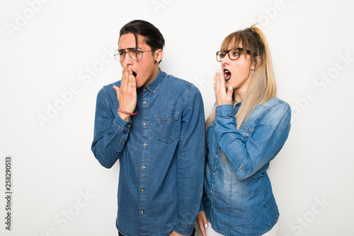 Young couple with glasses yawning and covering wide open mouth with hand
