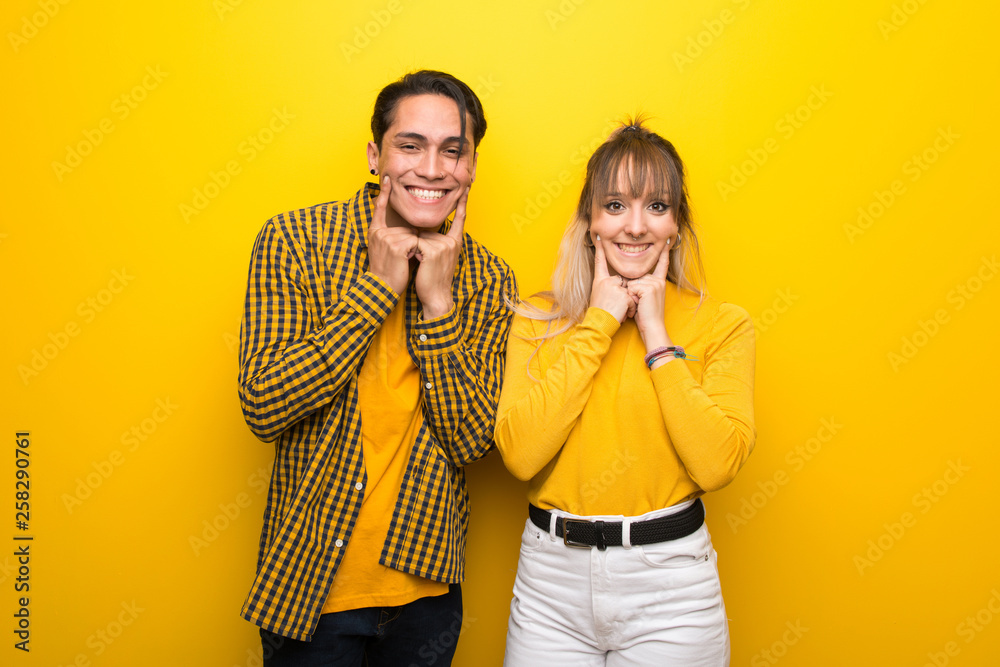 Young couple over vibrant yellow background smiling with a happy and pleasant expression Young couple over vibrant yellow background smiling with a happy and pleasant expression