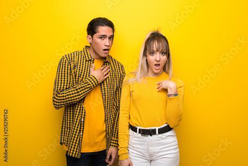 Young couple over vibrant yellow background surprised and shocked while looking right © luismolinero