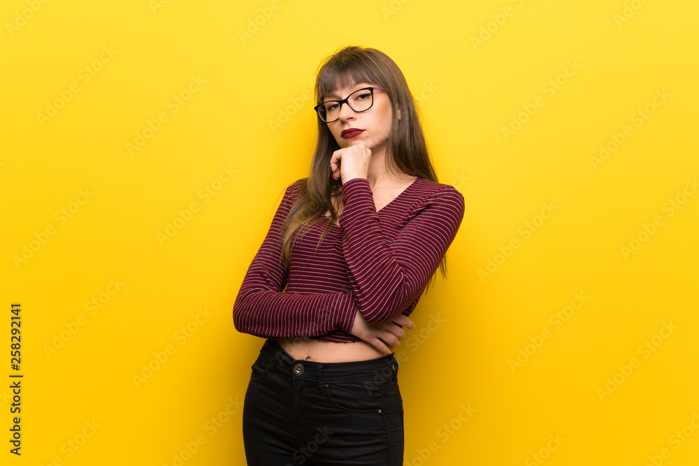 Woman with glasses over yellow wall thinking Woman with glasses over yellow wall thinking