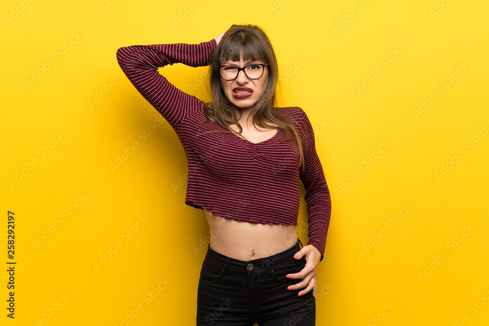 Obraz premium Woman with glasses over yellow wall frustrated and takes hands on head