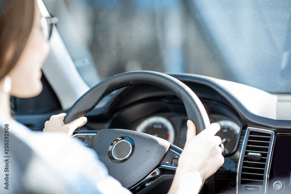 Woman holding steering wheel while driving a car, close-up view