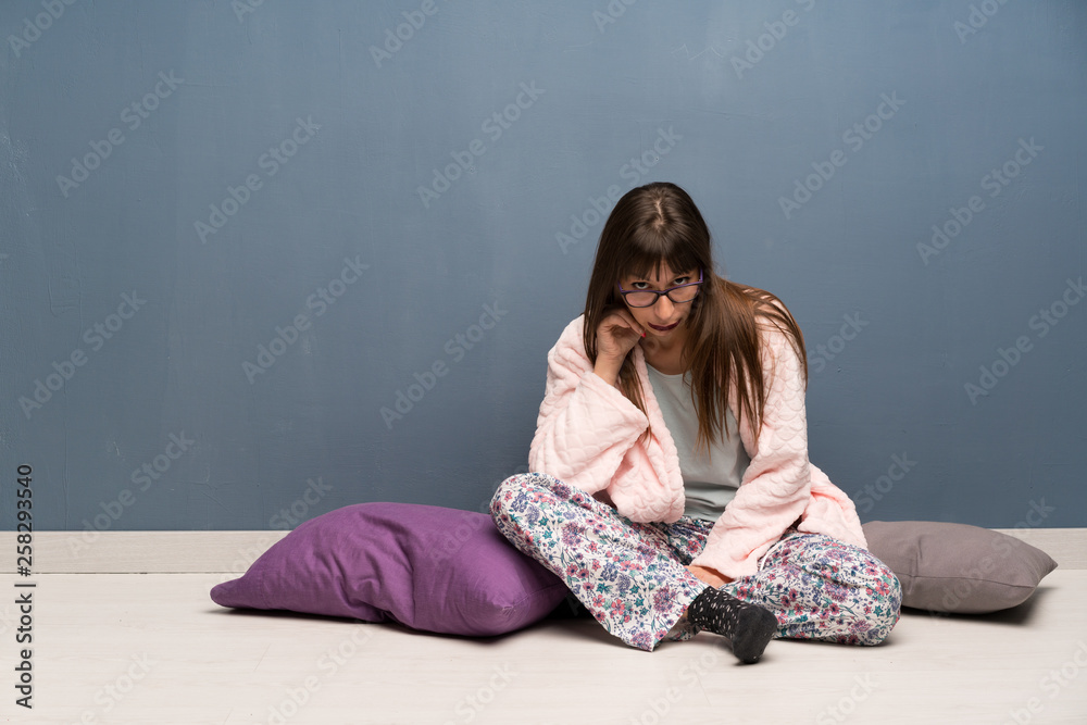 Woman in pajamas on the floor with glasses and surprised Woman in pajamas on the floor with glasses and surprised