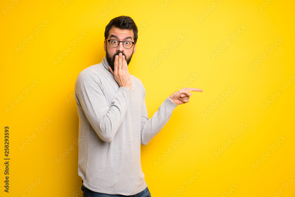 Man with beard and turtleneck pointing finger to the side with a surprised face Man with beard and turtleneck pointing finger to the side with a surprised face