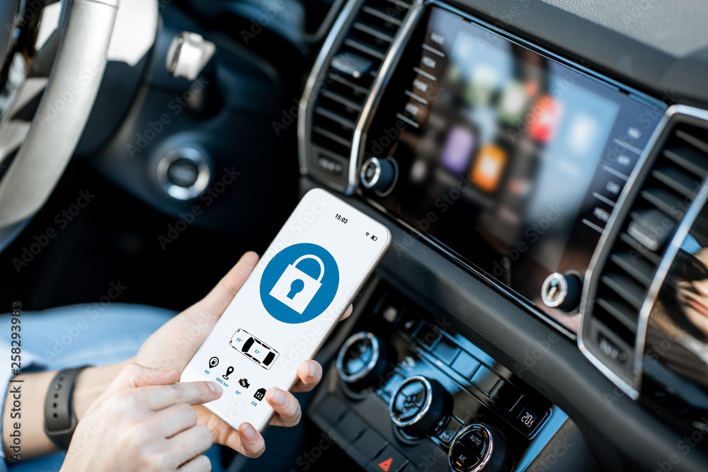 Obraz premium Close-up of a smart phone with car alarm application, controlling a vehicle in the car