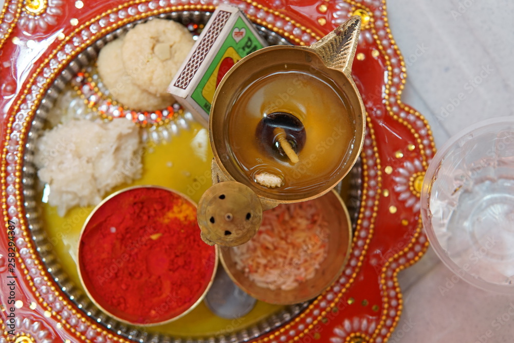 An auspicious plate or puja thali  used in  Hindu celebrations and festivals to worship gods or newly weds during weddings contains lamp, rice and other worship materials