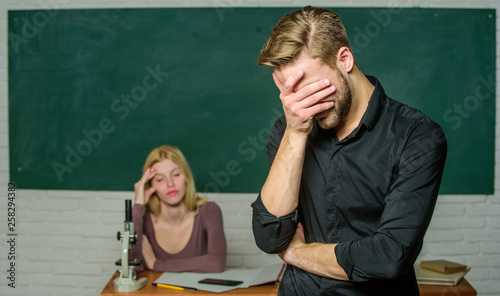 He left a lesson unlearned. University or college student covering face. Male student with examiner at examination. Handsome man standing in classroom with teacher. High school student saying lesson photo