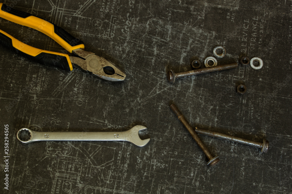 Tool set of pliers, wrenches, bolts and nuts on abstract grey surface Tool set of pliers, wrenches, bolts and nuts on abstract grey surface