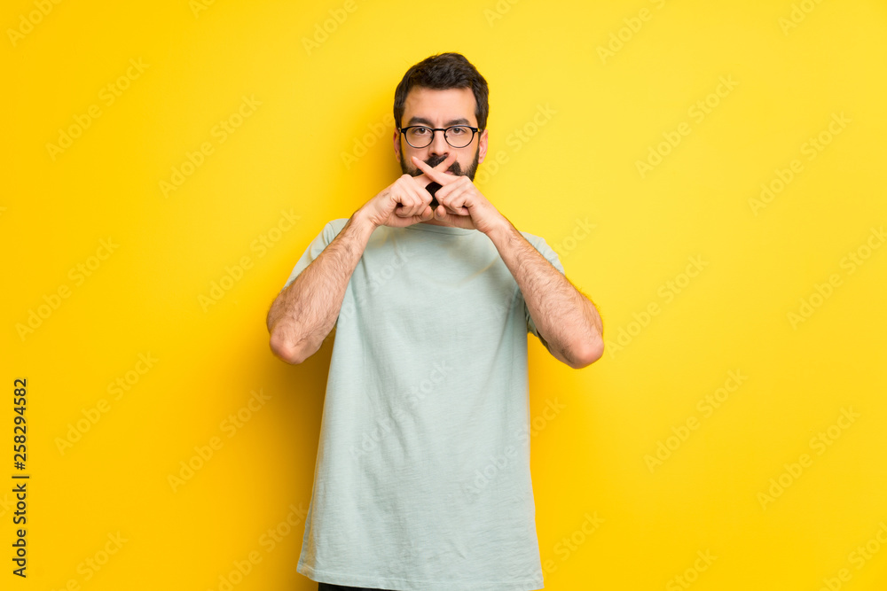 Man with beard and green shirt showing a sign of silence gesture Man with beard and green shirt showing a sign of silence gesture