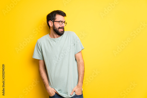 Man with beard and green shirt is a little bit nervous and scared pressing the teeth