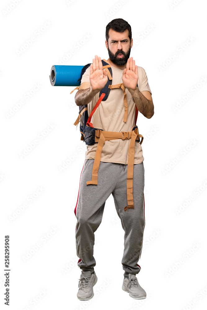 Hiker man making stop gesture and disappointed over isolated white background Hiker man making stop gesture and disappointed over isolated white background