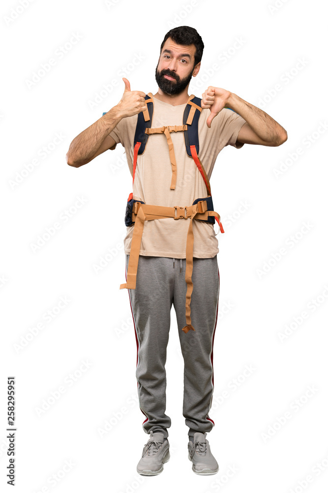 Hiker man making good-bad sign. Undecided between yes or not over isolated white background Hiker man making good-bad sign. Undecided between yes or not over isolated white background