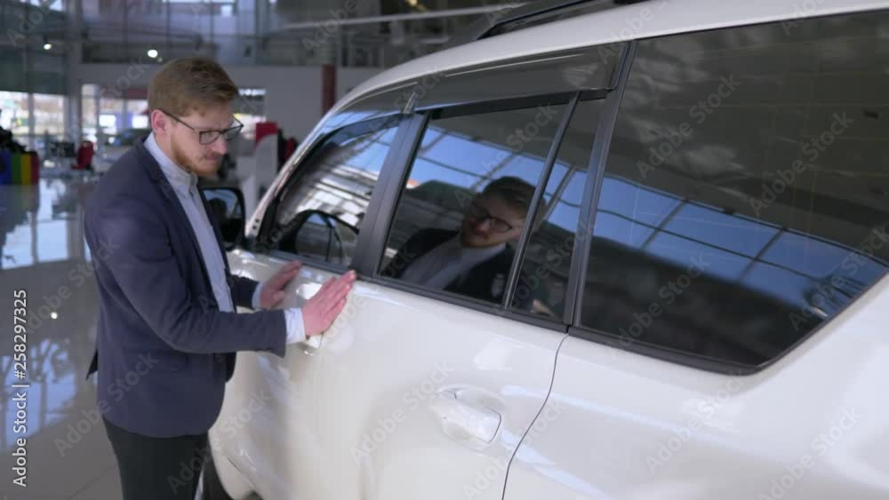car dealership, blissful buyer man into glasses with enjoyment stroking new vehicle gently smiling at Auto sale center close-up car dealership, blissful buyer man into glasses with enjoyment stroking new vehicle gently smiling at Auto sale center close-up
